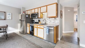 Een moderne keuken met roestvrijstalen apparatuur, houten kastjes en een betegelde achterwand.