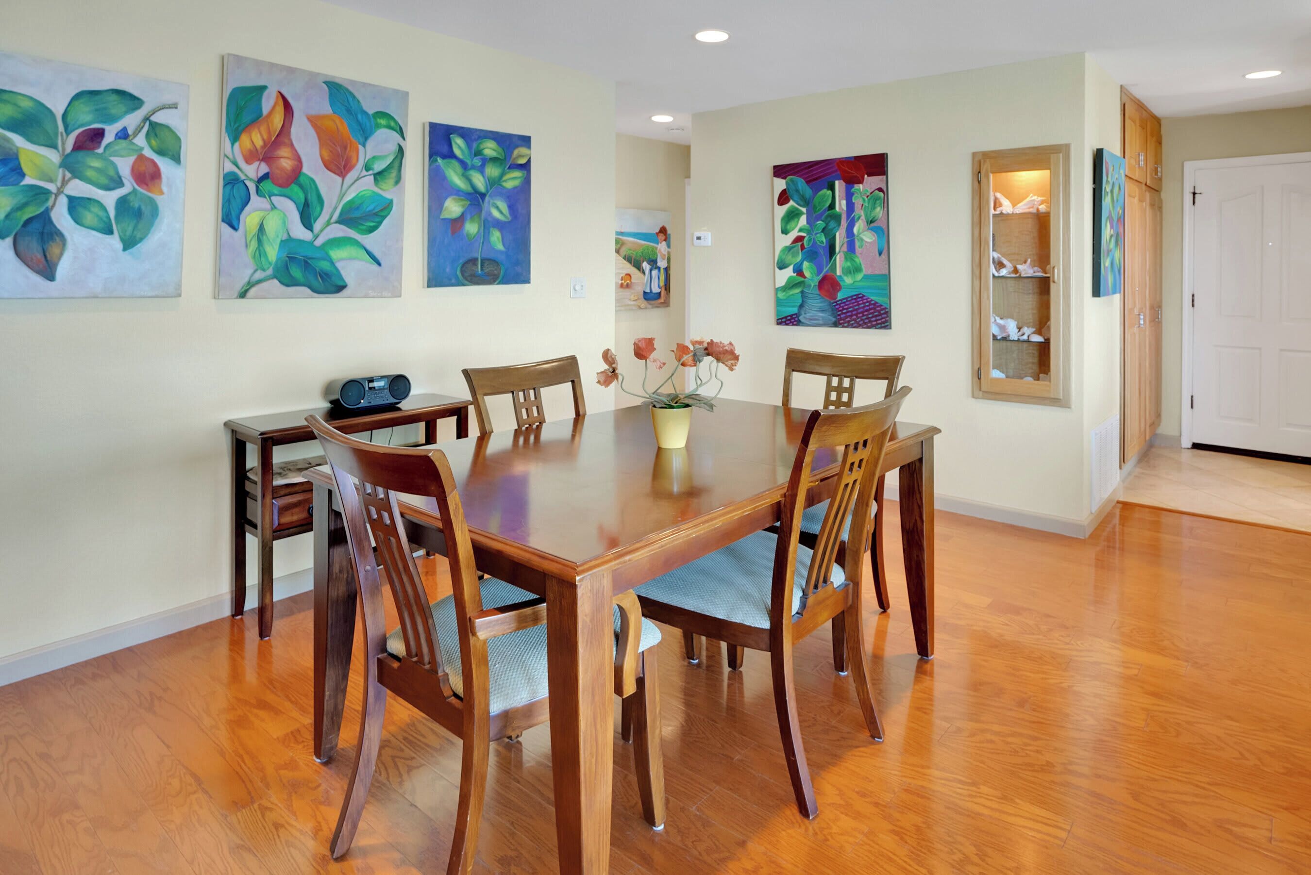 Un comedor con una mesa de madera, seis sillas y un jarrón con flores.