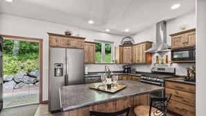 Une cuisine moderne avec des meubles en bois, des appareils en acier inoxydable et un  îlot central doté de tabourets de bar.