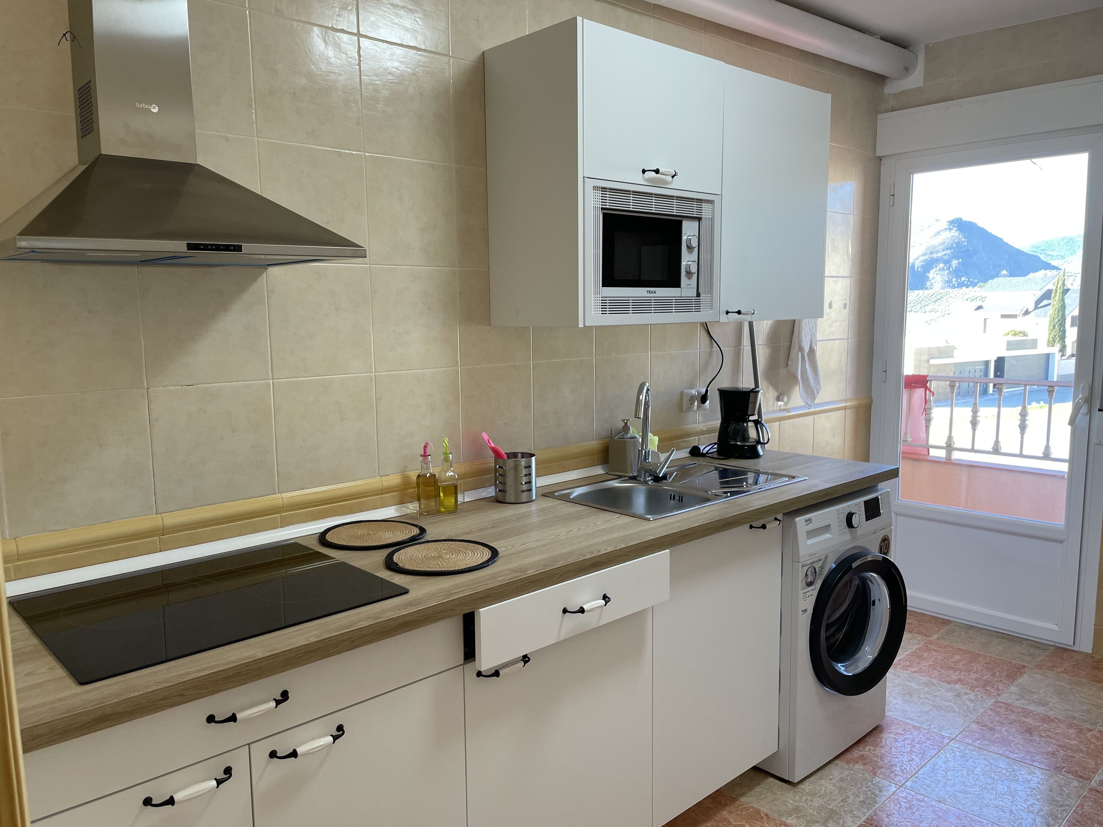 Una cocina moderna equipada con microondas, cafetera y lavadora.