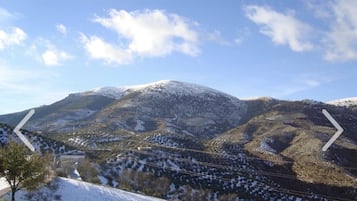 Paisaje montañoso con picos nevados y un valle con edificios dispersos.