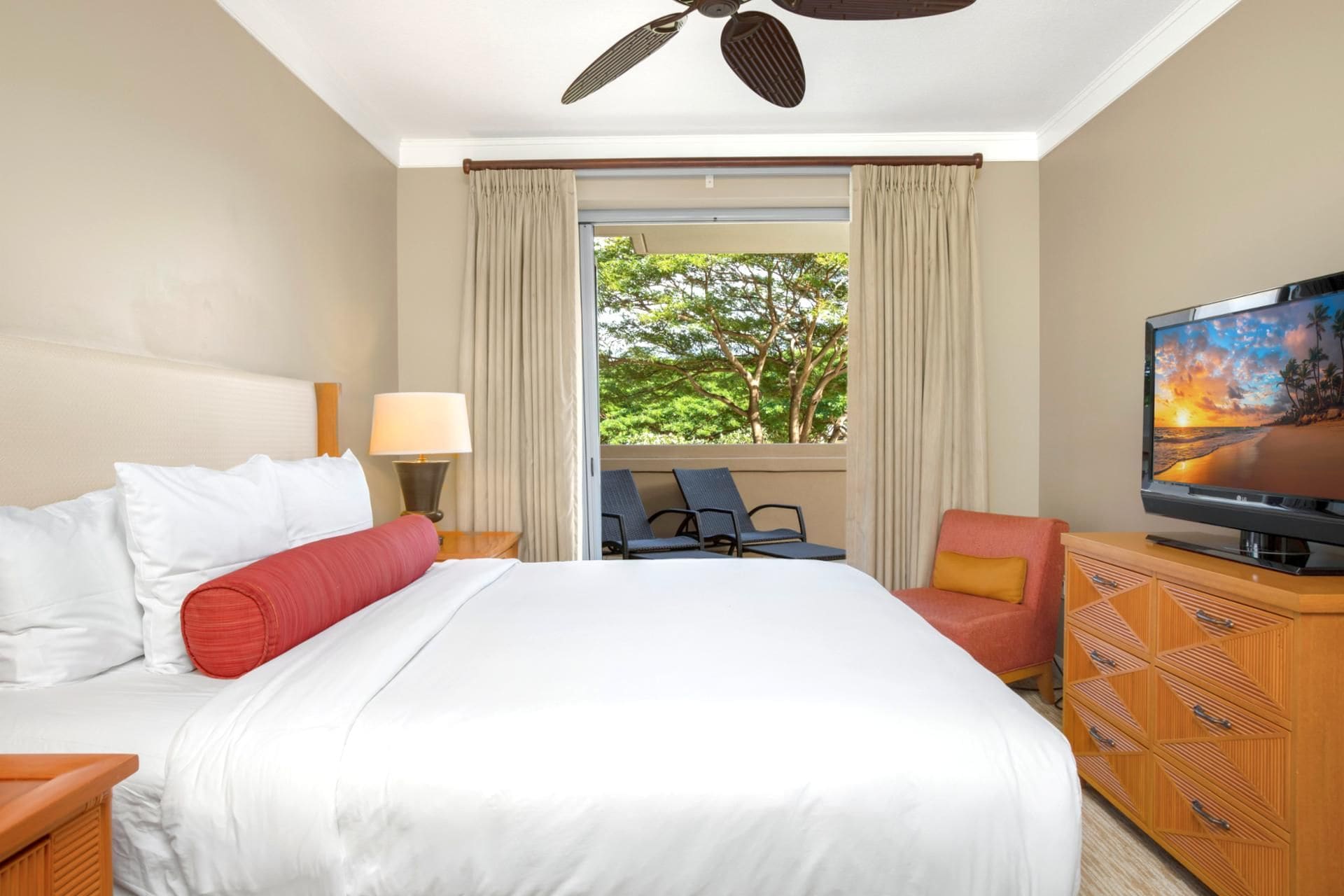 A hotel room with a bed, a TV, a desk, a chair, and a window with curtains.