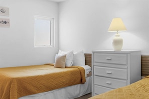 A bedroom with a bed, a nightstand, a lamp, a dresser, and a window. - Enchanted Woods Retreat Branson (Branson)