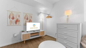 Une chambre moderne équipée d’une télévision, d’un bureau, d’une lampe et d’une armoire.