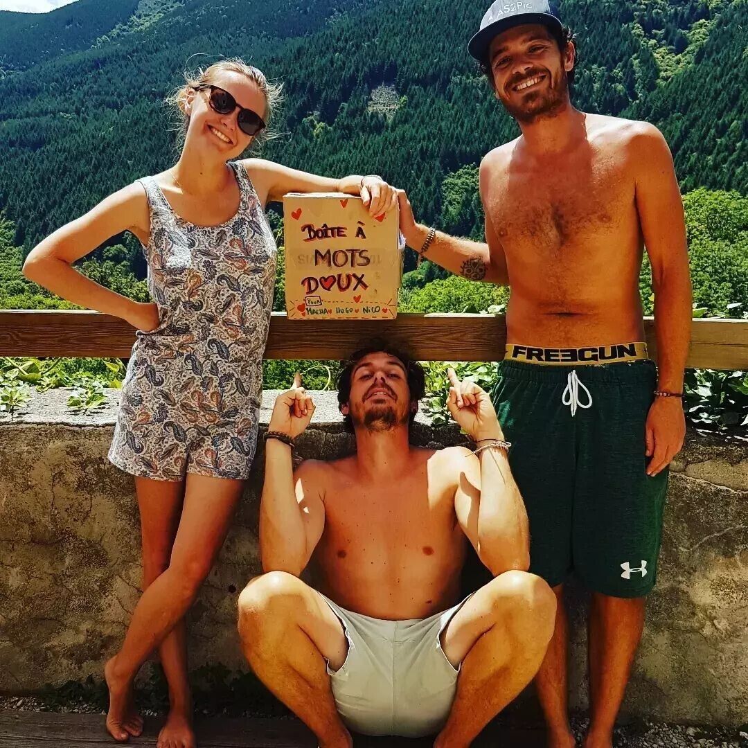 Three people posing with a sign in a natural setting.