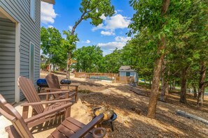A backyard with a barbecue grill, two Adirondack chairs, a small shed, and a wooden fence. - Whispering Woods Retreat Branson (Branson)