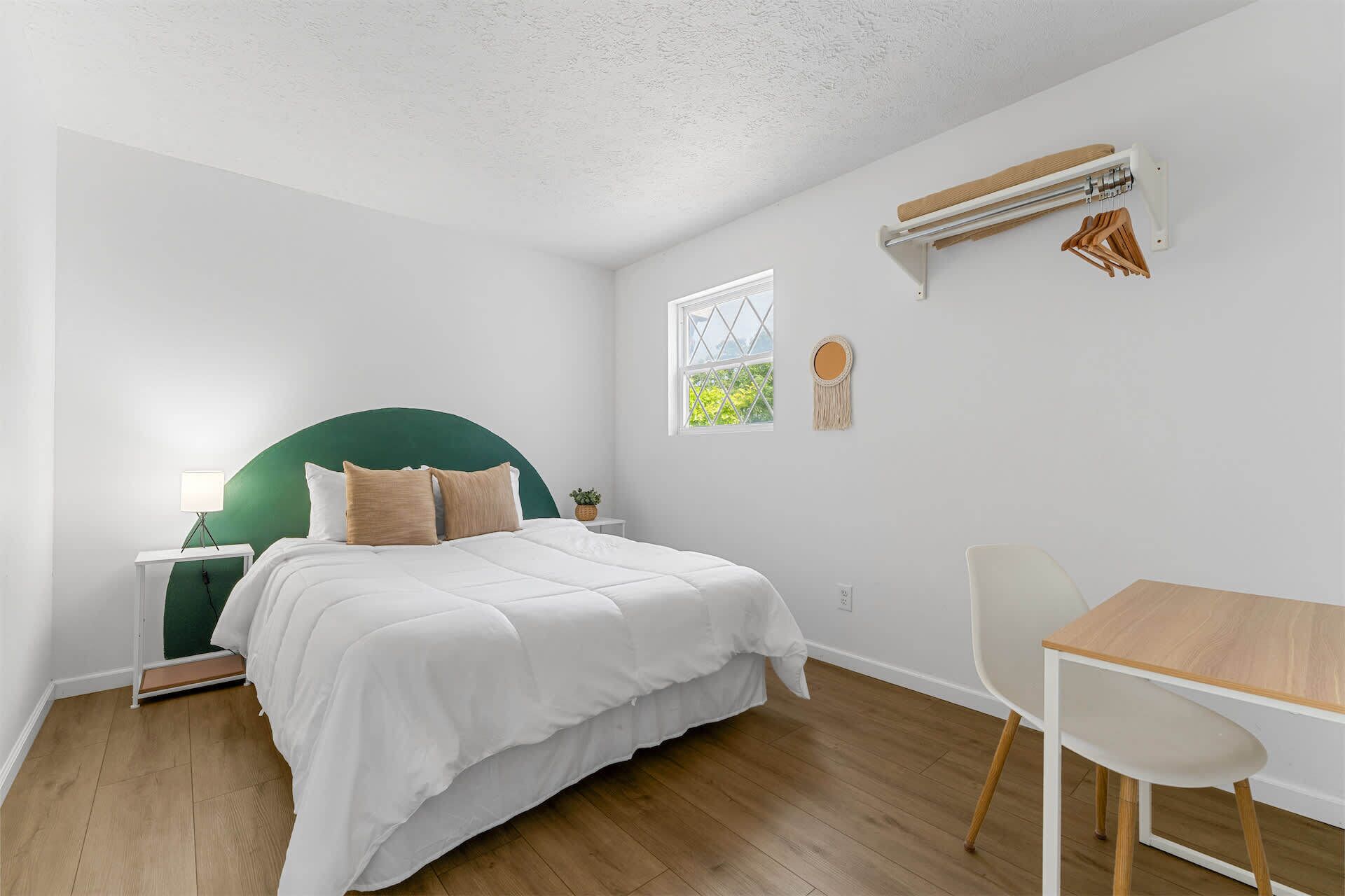 Une chambre à coucher avec un lit, une table de chevet, une chaise et une fenêtre donnant sur un beau paysage.