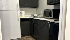 Una cocina compacta equipada con refrigerador, microondas y lavavajillas.
