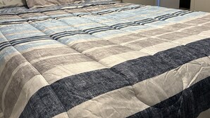 Un dormitorio con cama, una puerta que da a una cocina y una pared blanca.