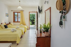 A hotel room with three beds, a wooden dresser, a mirror, a plant, and a window with curtains. - Apartment 'Studios Asterias  4' with Shared Terrace, Wi-Fi and Air Conditioning (Astipalea)