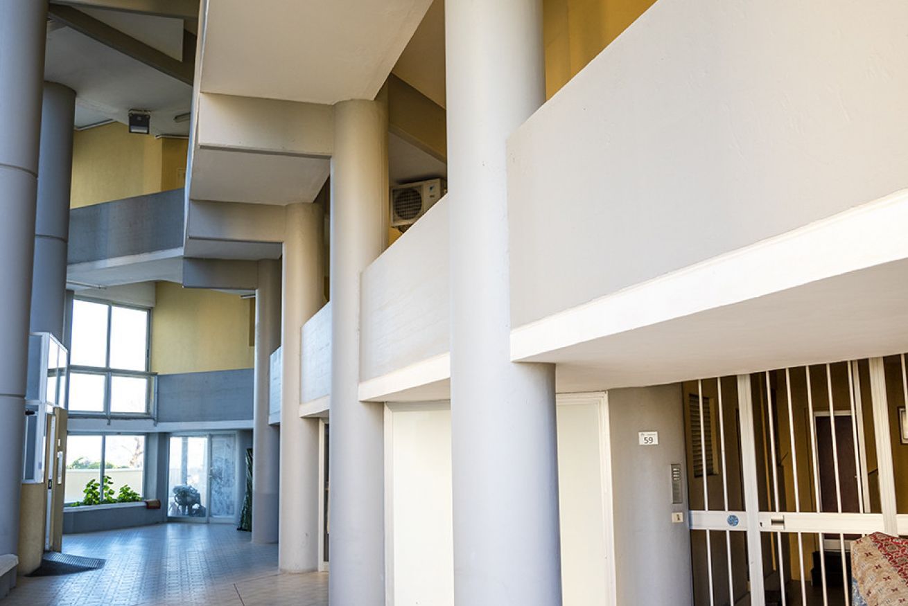 Un intérieur à plusieurs niveaux, doté d’un espace central ouvert, de colonnes et d’une zone délimitée par une grille.