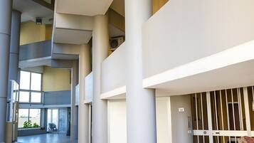 Un intérieur à plusieurs niveaux, doté d’un espace central ouvert, de colonnes et d’une zone délimitée par une grille.