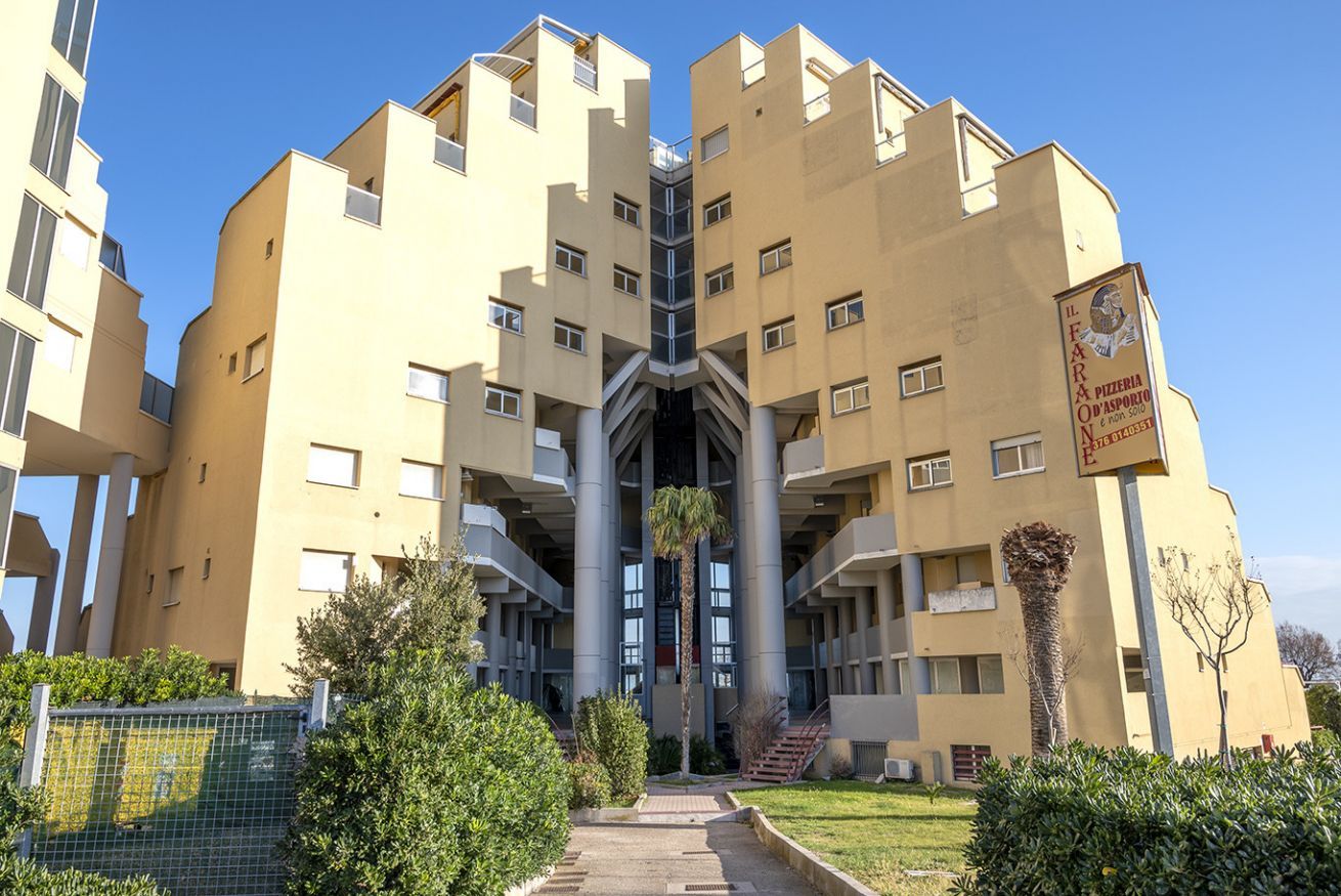 Un immeuble à plusieurs étages doté d’un atrium central, de balcons et d’une enseigne indiquant qu’il s’agit d’une pizzeria.