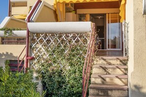 A staircase leading to a building entrance with a yellow awning and a white lattice fence.