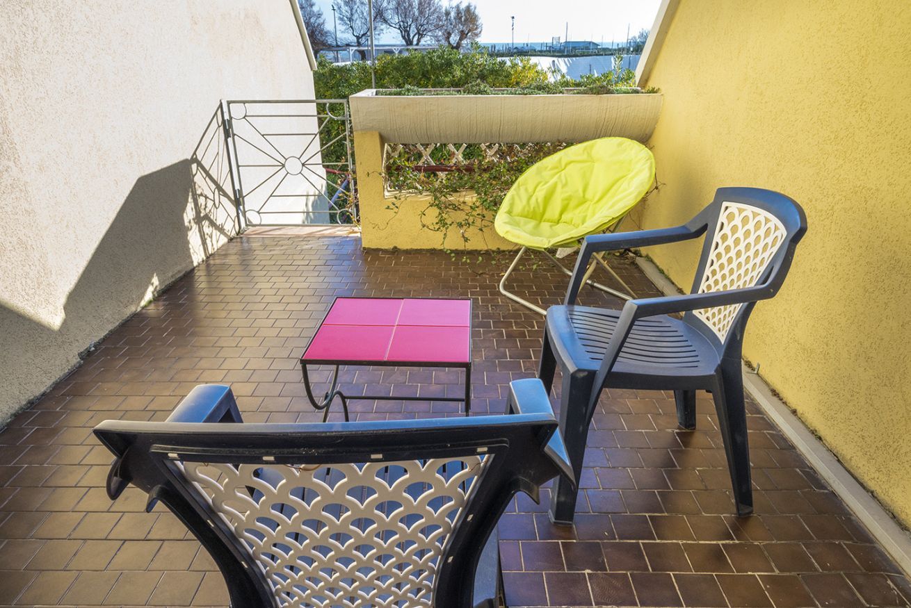 Une terrasse avec une table et des chaises, un mur jaune et une vue sur l’eau.