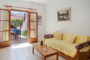 Ein Wohnzimmer mit gelber Couch, einem Holztisch und einer Treppe, die zu einem Außenbereich führt.