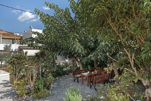 A patio with a table and benches, surrounded by trees and plants.