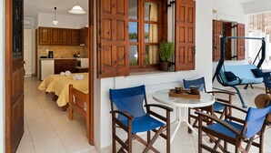 A room with a bed, wooden chairs, a round table, and a window with open shutters. - Apartment 'Studios Asterias 3' with Shared Terrace, Wi-Fi and Air Conditioning (Astipalea)