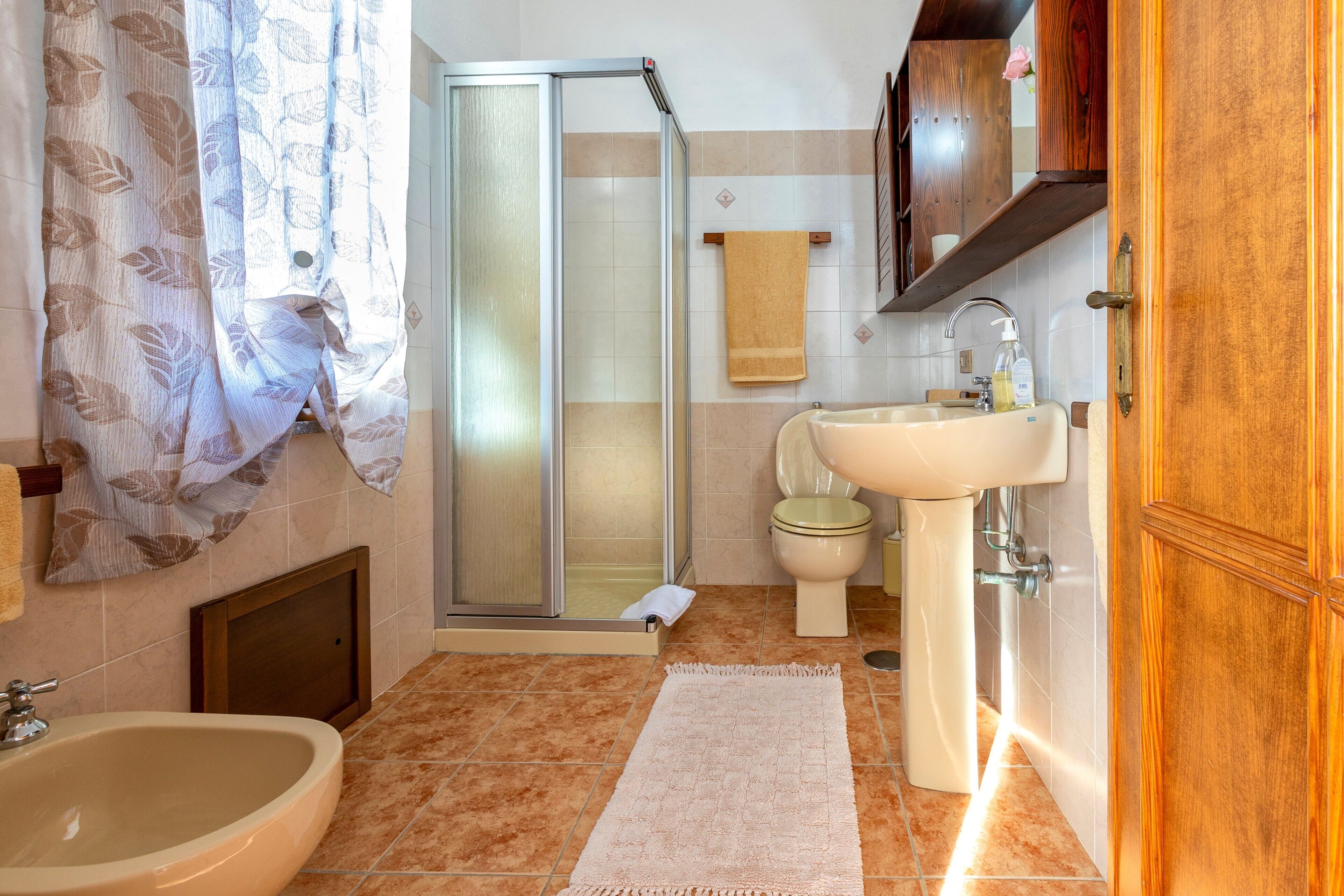 Un baño con ducha, lavabo, inodoro y toallero.