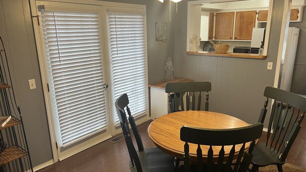 A dining area with a round wooden table and four chairs, a kitchen visible through a doorway, and a ceiling fan. - Great location close to all Tulsa has to offer.  Pet friendly, fenced back yard! (Tulsa)
