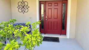 Una puerta roja con un felpudo que dice 'Home Sweet Home'.