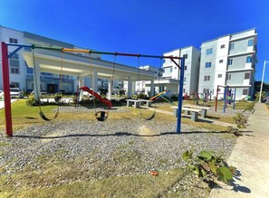 Children can play on swings and a slide in this outdoor playground area.