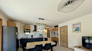 Une cuisine moderne avec un îlot central, des chaises noires et une table à manger.