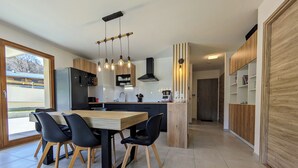 Une cuisine moderne avec une table et des chaises en bois, un four encastré et une grande fenêtre.