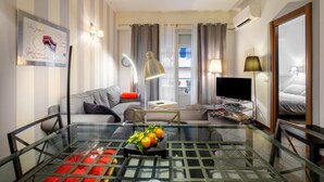 A modern living room with a glass coffee table, a sofa, a TV, and a lamp. - Apartment 'Florence' with Balcony, Wi-Fi and Air Conditioning (Nice)