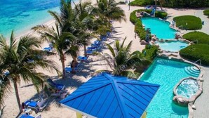 Un complexe hôtelier doté d’une plage, d’une piscine et de palmiers.