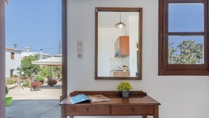 A room with a wooden desk, a mirror, a potted plant, and a view of the outside.