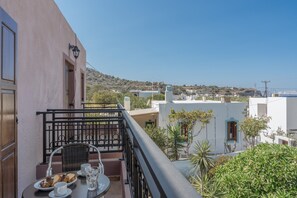 A balcony with a table set for breakfast, a view of the town, and a mountain in the distance. - Studio Apartment 'Frantzis  5' with Sea View, Wi-Fi and Air Conditioning (Nisyros)