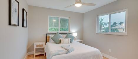 A bedroom with a bed, a nightstand, a window, and a ceiling fan.