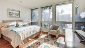 Une chambre à coucher avec un lit, une chaise, un bureau et de grandes fenêtres.