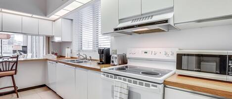 A modern kitchen with white cabinetry, a built-in oven, a microwave, and a coffee maker.