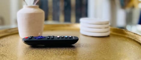 A remote control on a tray with a vase and a plant.