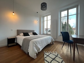 Ein modernes Schlafzimmer mit Bett, Nachttischen, Schreibtisch und Stuhl.