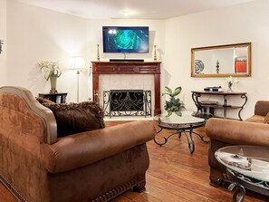 Ein Wohnzimmer mit Kamin, einem darüber montierten Fernseher und zwei Sofas.