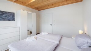 Un dormitorio con cama, armario, espejo y un cuadro en la pared.