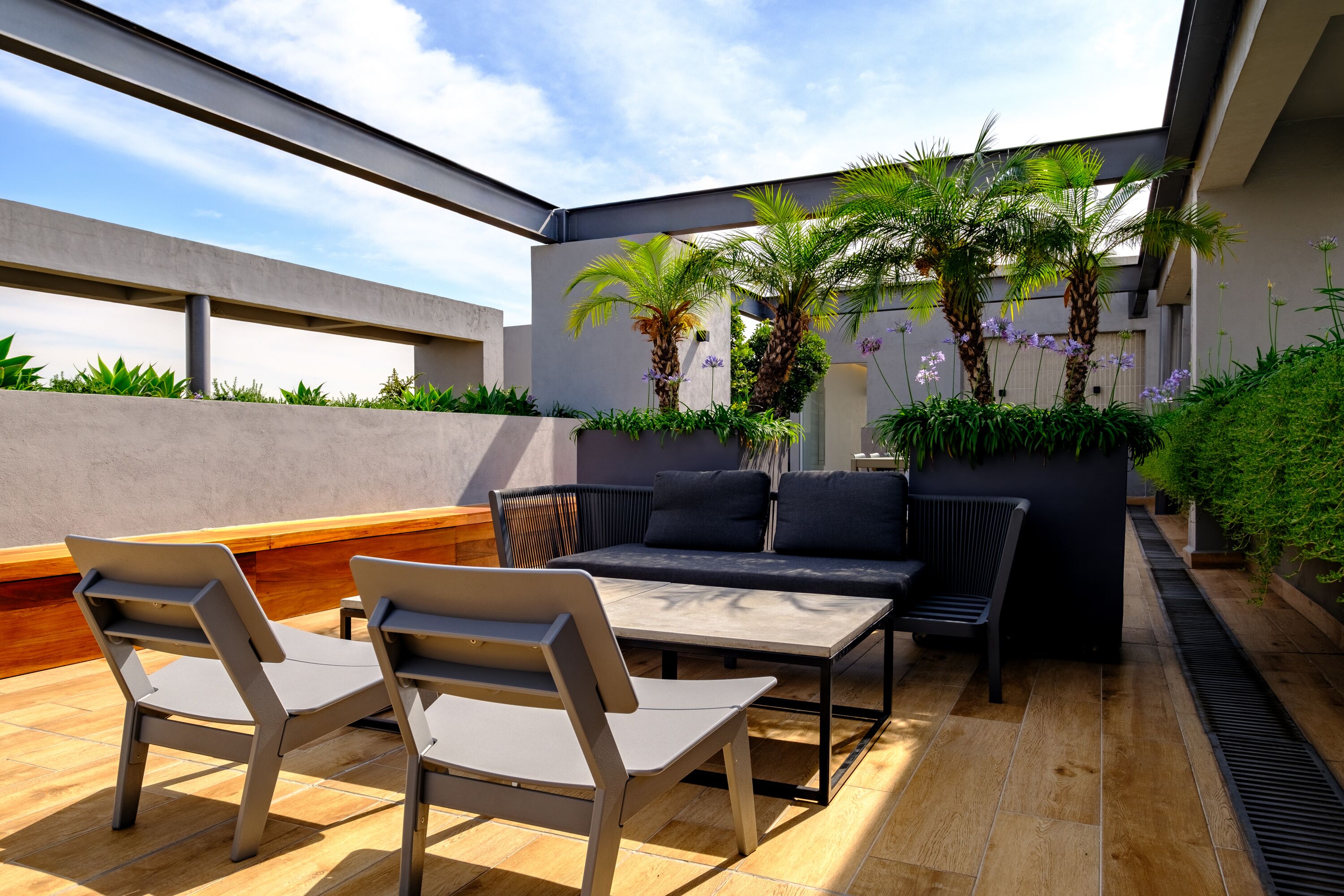 Un patio al aire libre con un sofá, dos sillones y una mesa.