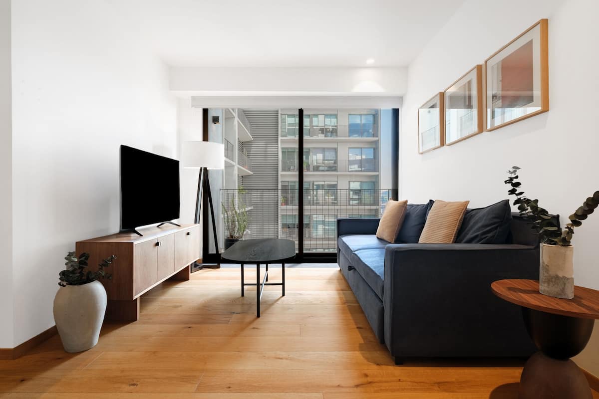 A modern living room with a sofa, a TV, a small table, and a potted plant.