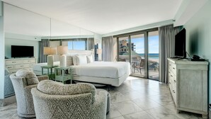 A hotel room with a bed, two armchairs, a TV, a desk with a lamp, and a view of the beach. - Modern Luxury, Gulf Views: Renovated 5th-Floor Oasis at Sandestin Golf and Beach Resort! (Miramar Beach)