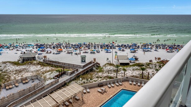A beach with a wooden deck and a pool.