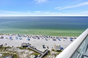 A beach with umbrellas and people, a clear sky, and a view of the ocean. - Sky-High Serenity: 15th-Floor Studio Retreat with Unobstructed Gulf Views at Sandestin Golf and Beach Resort! (Miramar Beach)