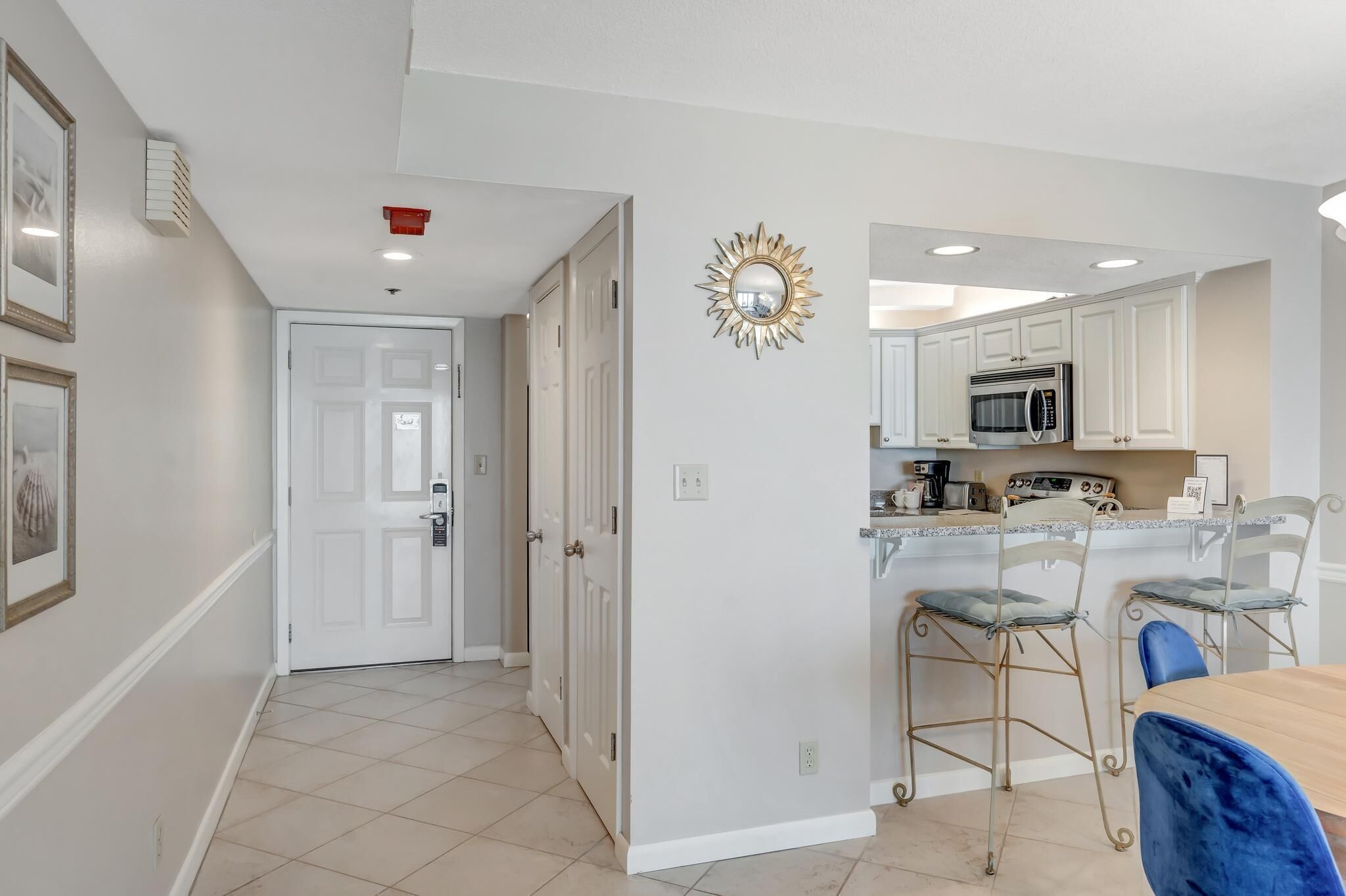 A modern kitchen with white cabinets, a microwave, and a bar area with stools.