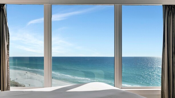 A room with a large window overlooking a beach and ocean. - "Serene Sunrises: Cozy 10th-Floor Haven with Gulf Views in Beachside Two!" at Sandestin Golf and Beach Resort! (Miramar Beach)