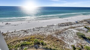 Una playa con vista despejada al océano y una zona arenosa con vegetación escasa.