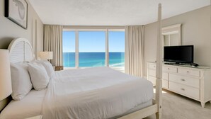 Habitación de hotel con una cama grande, televisor y vista al océano.
