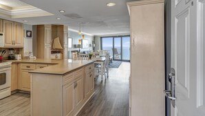 A spacious kitchen with wooden cabinets, a central island, and a dining area with a view of the ocean.