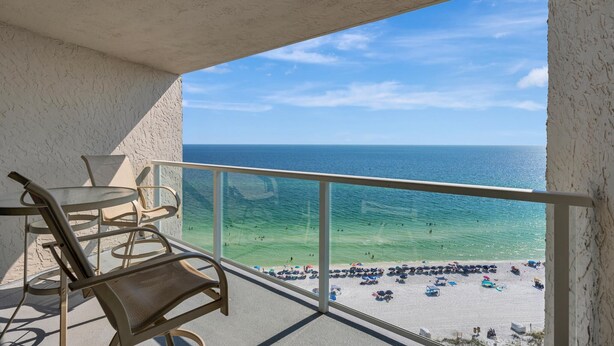 A balcony with a view of the beach and ocean.
